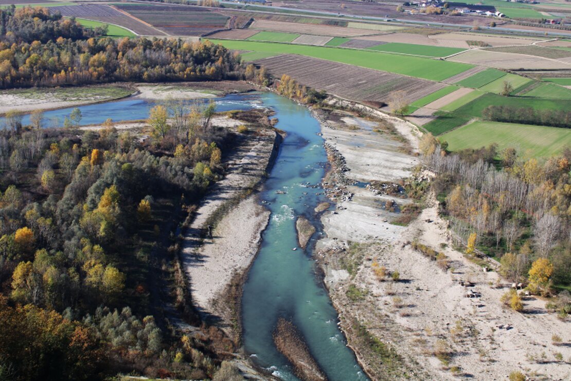 Drone che sorvola una valle con fiume e pendii boscati